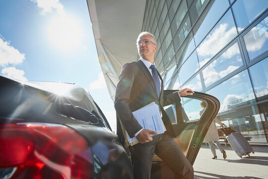 Businessman Arriving At Airport Getting Out Of Town Car