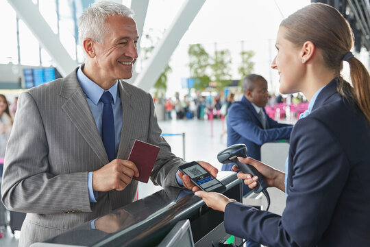 Customer service representative scanning smart phone QR code boarding pass at airport check-in counter