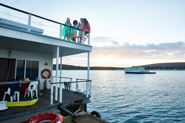 Fototapeta na wymiar Young adult friends hanging out on deck of summer houseboat on ocean