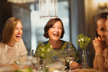 Laughing women friends dining and talking at restaurant table