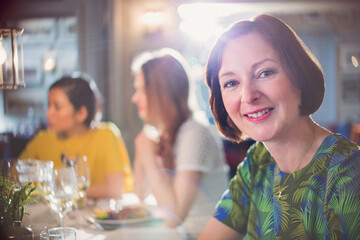 Portrait smiling woman dining with friends at restaurant table