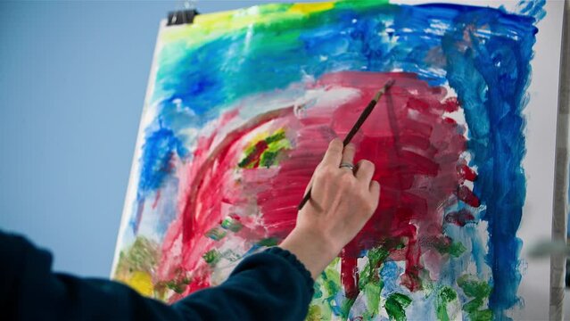 contemporary art, a young talented woman draws a creative picture with help of paint and brushes, close-up