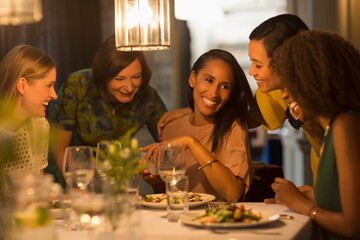 Smiling friends celebrating woman‚Äôs birthday at restaurant table