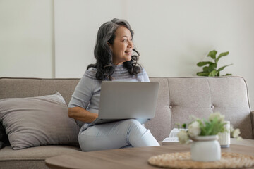 Portrait of middle aged woman sitting at with laptop at home