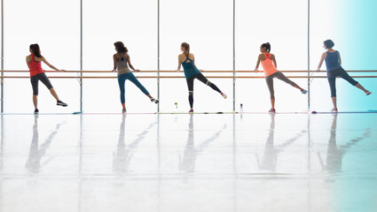 Women exercising at barre in exercise class gym studio
