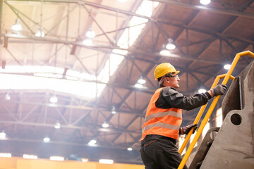 Steel worker climbing ladder in factory