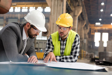 Manager and engineer reviewing blueprints in steel factory