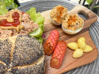 Tuna salad bagel burger with devil egg and grilled pink sausage 