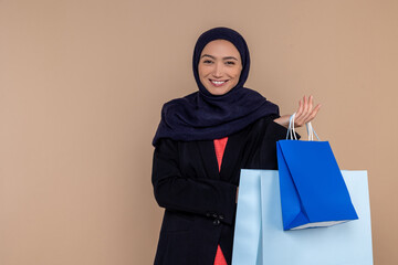 Smiling Muslim woman in hijab standing with shopping bags