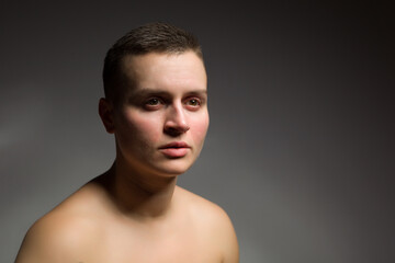 portrait of young woman with short hair and bare shoulder on grey bakground