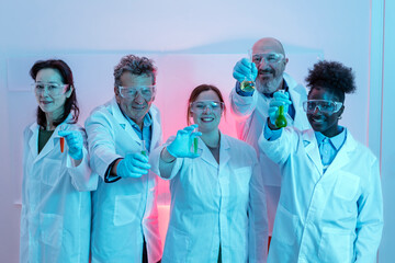 group photo of research scientists wearing a white coat and jokingly showing chemical laboratory test tubes in their hands