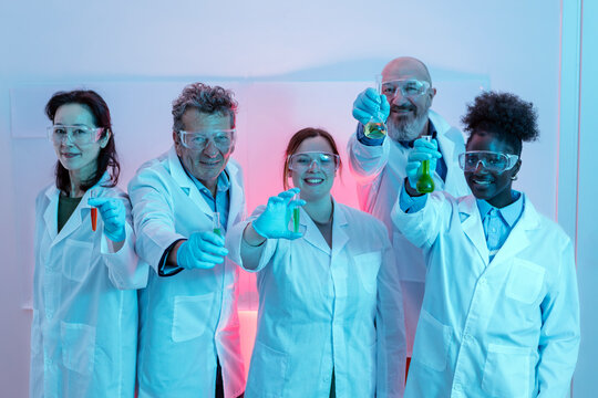 group photo of research scientists wearing a white coat and jokingly showing chemical laboratory test tubes in their hands