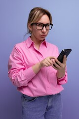Fototapeta premium young successful blond careerist leader woman in a pink blouse and glasses solves work issues on the phone