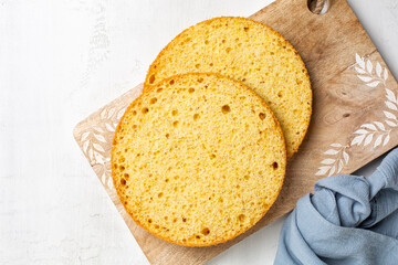 Cooking and baking round vanilla sponge cake or chiffon cake, two cut layers with texture. Homemade culinary, dessert. Top view, white background. - obrazy, fototapety, plakaty