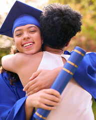 Proud Mother Celebrating And Hugging Teenage Daughter Wearing Graduation Robes Outdoors