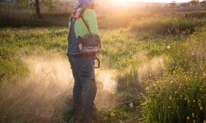 man moving the grass at sunset