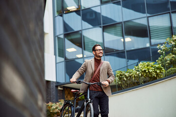 Low-angle view businessman pushing a bicycle outside, dressed in a nice suit.