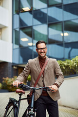 Fototapeta na wymiar A smiling businessman with a briefcase walking on foot with a bicycle.
