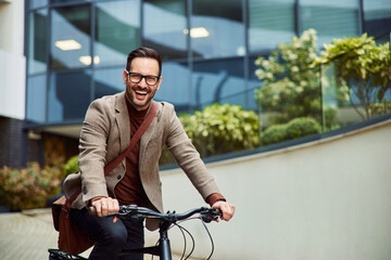 Portrait of a happy businessman riding a bicycle in front of the company.