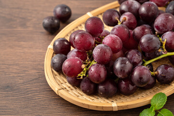 Delicious bunch of grapes fruit on a plate over wooden table background.