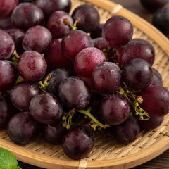Delicious bunch of grapes fruit on a plate over wooden table background.