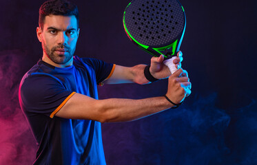 Padel tennis player with racket. Man athlete with paddle racket on court with neon colors. Sport...