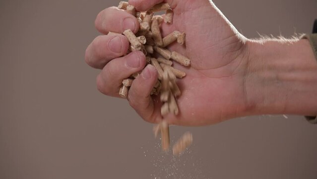 hand pouring wood pellets in slow motion