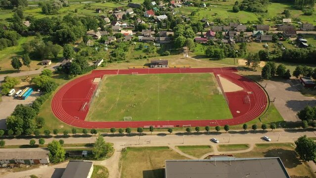 Sports field, city stadium filmed from above with a drone. Athletes play football in the stadium.