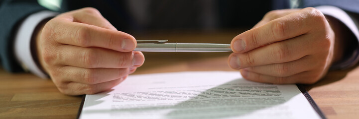 Businessman in suit holding ballpoint pen over document and thinking about signing closeup. Contract for employment concept