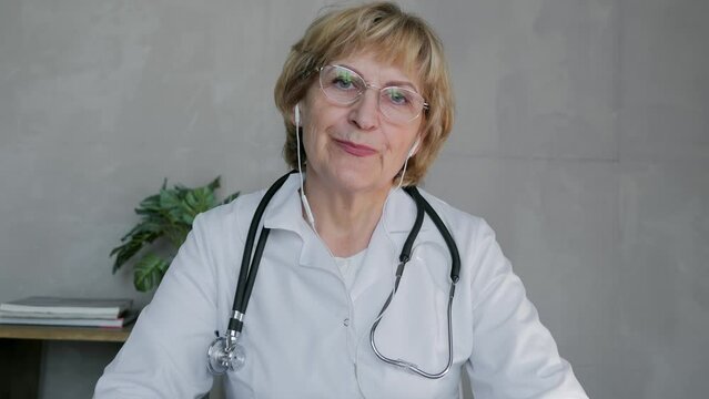 Online speech of the chief physician of the clinic, an adult blonde doctor, a medical worker in a white coat and glasses communicates by video call, speaks at an online conference at a medical forum