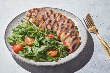 Fried chicken fillet and fresh vegetable salad with tomatoes.