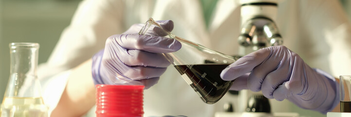 Scientist chemist holding in his hands flask with oil in chemical laboratory closeup. Quality...