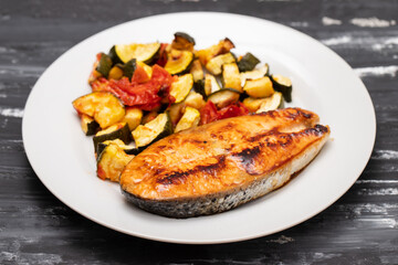 Fried salmon with vegetables on white plate