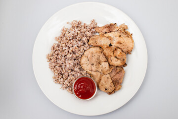 boiled green buckwheat with turkey and sauce on a white plate