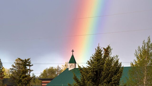 Timelapse zoom of colorful rainbow over church, pride blessing concept