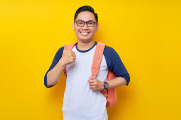 Portrait of smiling happy young Asian boy student wearing casual clothes and backpack showing...