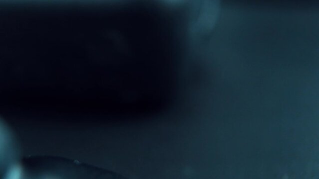 A cinematic macro zoom in shot of a wireless black earbuds earphones upside down, studio lighting, 120 fps, slow motion, Full HD