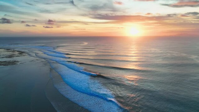 Panning drone shot of a beautiful golden Indonesian sunset, at the internationally renowned surf break on Grajagan Bay, Banyuwangi, Java.