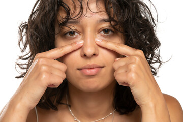 Young etnic woman touches her nose with her fingers on a white background. front view