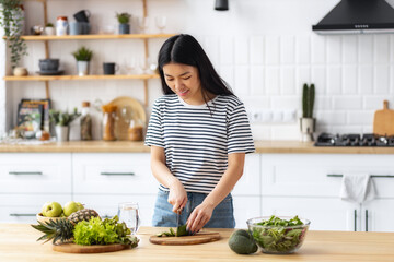 Young Asian woman cooking healthy food while standing in the kitchen at home. Healthy lifestyle...