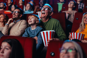 Excited senior man with granddaughter in cinema.