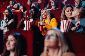 Multiracial couple watching fun movie in theater.
