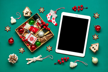 top view tablet with black digital screen, Christmas box and decor on green table Flat lay Holiday shopping list, Happy New Year, online shop, chooses gifts, makes purchases Mockup - 617008095