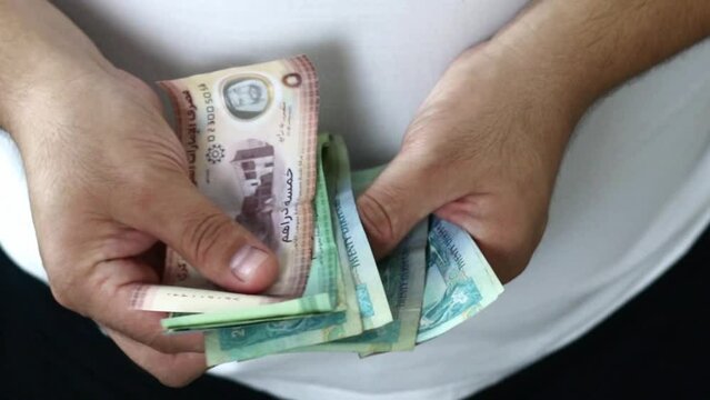 Hands counting dirham banknotes