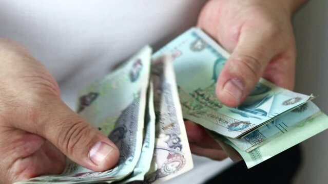 Hands counting dirham banknotes