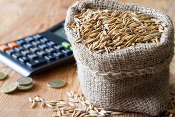 Sack of grain, calculator and coins, cereal prices and trade concept