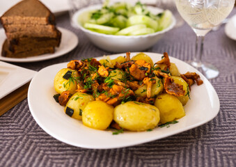 baked potatoes with chanterelles, served with herbs on white plate