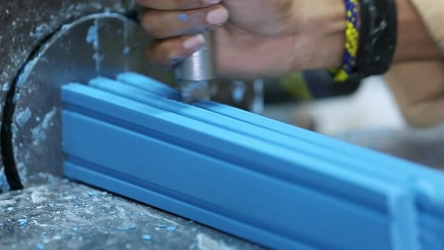 A close-up of a worker cutting bar soap as it comes through the extruder machine