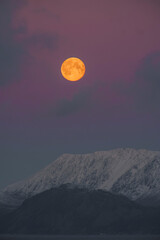 full moon over snow covered mountain landscape during dusk