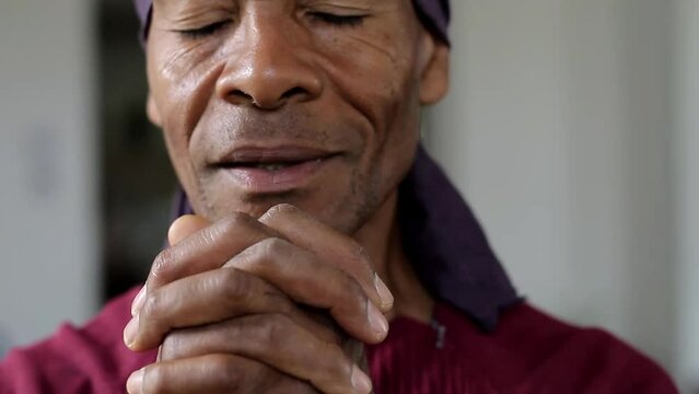 man praying to god with hands together Caribbean man praying with background with people stock footage